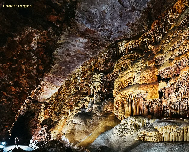 Spéléologue dans une grande grotte rocheuse aux formations complexes et éclairées à Meyrueis en Lozère 48