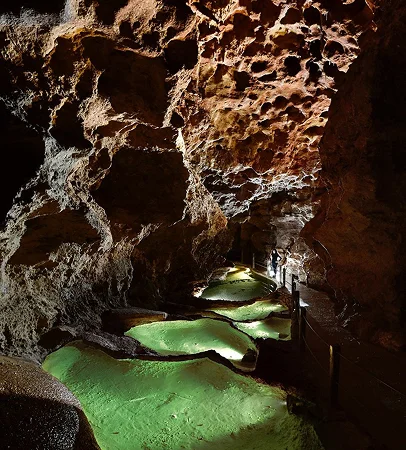 Grottes illuminées avec des bassins d'eau vert vif et un chemin de bois à Meyrueis en Lozère 48