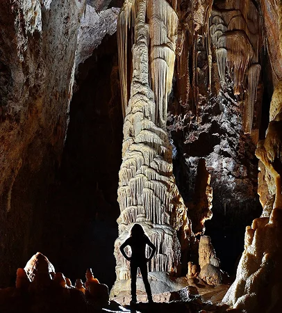 Silhouette d'une personne dans une grotte éclairée avec de grandes formations rocheuses à Meyrueis en Lozère 48