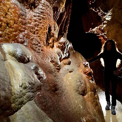 Spéléothèmes ruisselants dans une grotte avec une personne aux cheveux bouclés à Meyrueis en Lozère 48