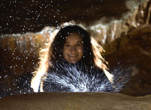 Une personne regarde une goutte d'eau en train de tomber, au sein de la grotte Rose