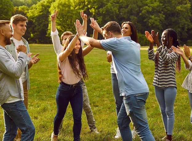 Jeunes adultes jouant à un jeu de groupe avec des high-fives et des applaudissements.